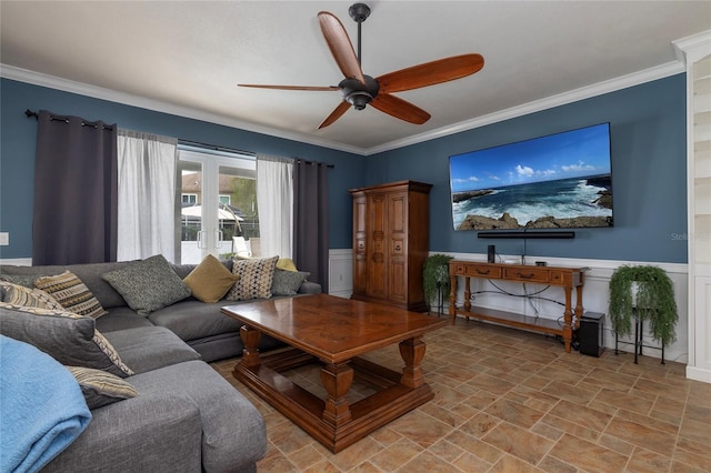 living area with ceiling fan, crown molding, stone finish floor, and wainscoting