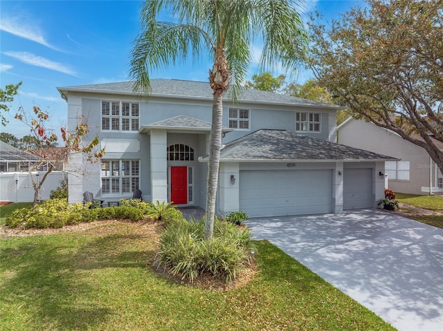 traditional-style house featuring a front lawn, an attached garage, driveway, and stucco siding