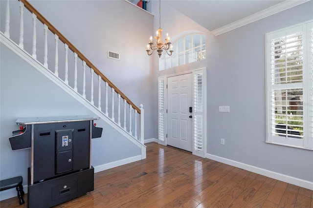 foyer featuring hardwood / wood-style floors, stairway, visible vents, baseboards, and ornamental molding