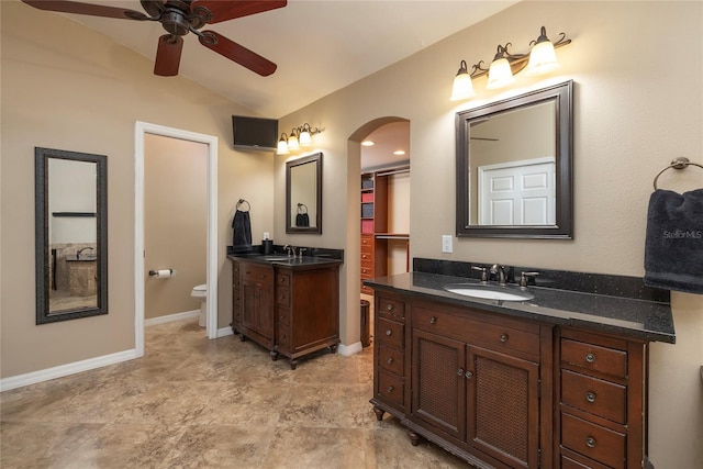 bathroom with toilet, lofted ceiling, two vanities, and a sink