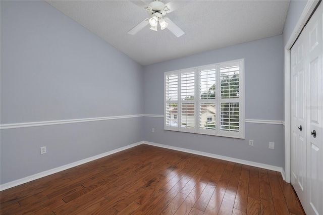 unfurnished bedroom with lofted ceiling, a ceiling fan, a closet, baseboards, and dark wood-style flooring