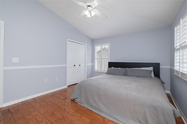 bedroom featuring ceiling fan, baseboards, lofted ceiling, wood finished floors, and a closet