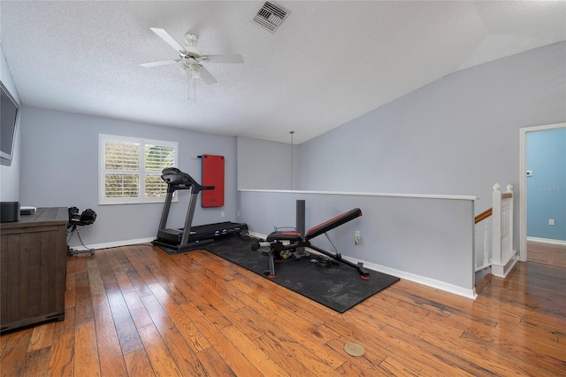 workout room with visible vents, ceiling fan, baseboards, hardwood / wood-style floors, and a textured ceiling