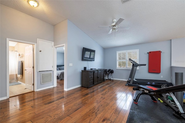 workout area featuring visible vents, vaulted ceiling, a textured ceiling, a ceiling fan, and wood-type flooring