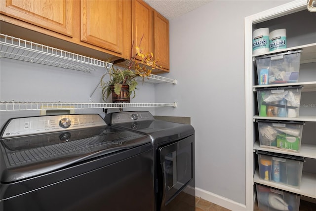 laundry area featuring cabinet space, washing machine and dryer, baseboards, and a textured ceiling