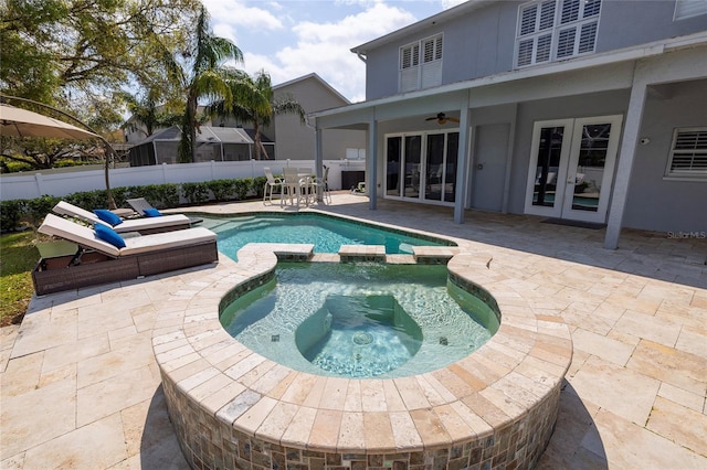 view of pool with a pool with connected hot tub, ceiling fan, fence, french doors, and a patio