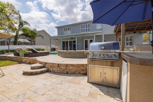 view of patio with exterior kitchen, area for grilling, fence, and a fenced in pool