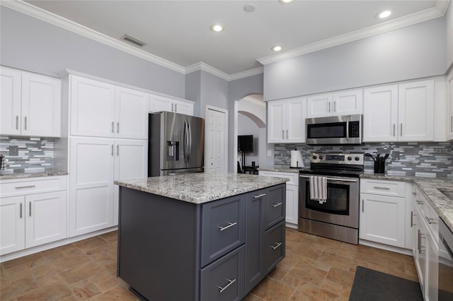 4859 Augusta Ave, Oldsmar, FL 34677 - kitchen featuring appliances with stainless steel finishes, arched walkways, ornamental molding, gray cabinetry, and stone finish flooring