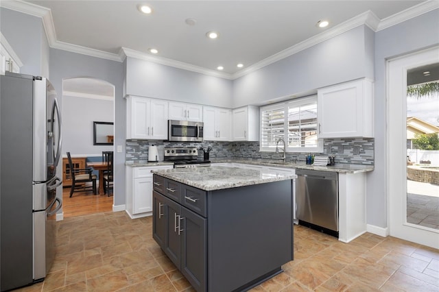 4859 Augusta Ave, Oldsmar, FL 34677 - kitchen with stainless steel appliances, light stone finish floors, arched walkways, white cabinets, and crown molding