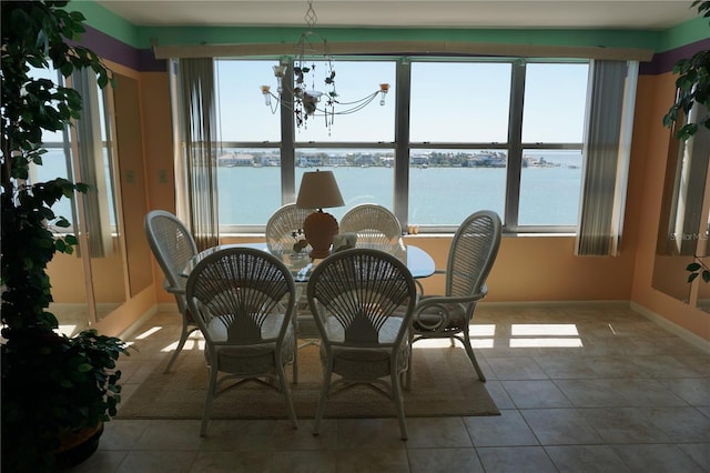 tiled dining area featuring an inviting chandelier, a water view, and a wealth of natural light