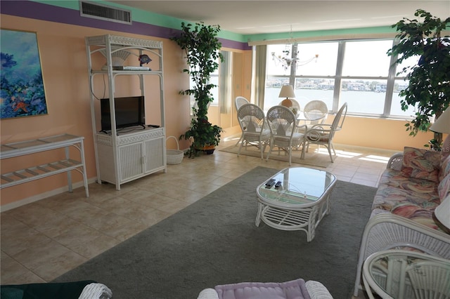 living area with tile patterned floors, visible vents, baseboards, and an inviting chandelier