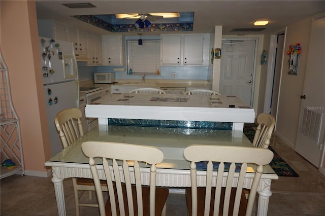 kitchen featuring tile patterned flooring, white appliances, white cabinets, and baseboards