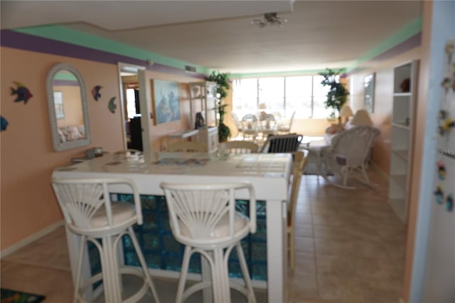 kitchen featuring tile patterned floors, a kitchen bar, and baseboards