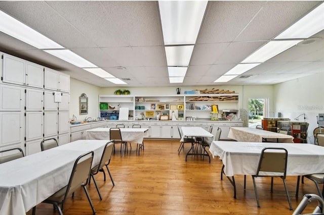 dining room featuring light wood-type flooring and a drop ceiling