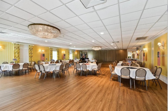 dining space with visible vents, a paneled ceiling, and wood finished floors