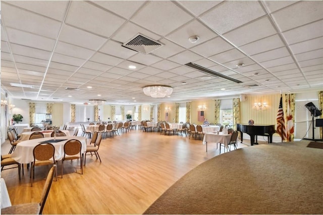 dining area with plenty of natural light, wood finished floors, visible vents, and a drop ceiling