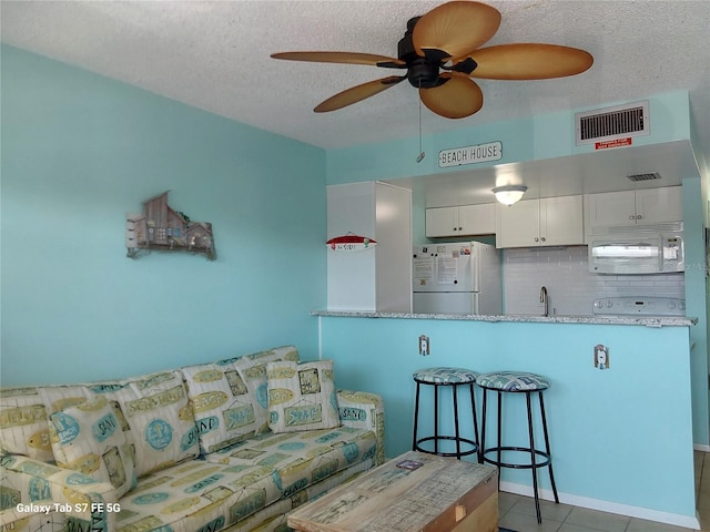 tiled living room featuring a ceiling fan, a textured ceiling, and a sink