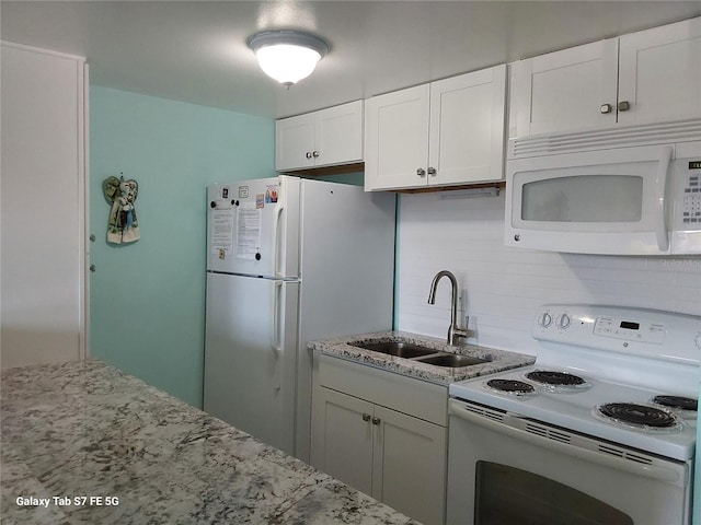 kitchen with white appliances, a sink, decorative backsplash, white cabinetry, and light stone counters