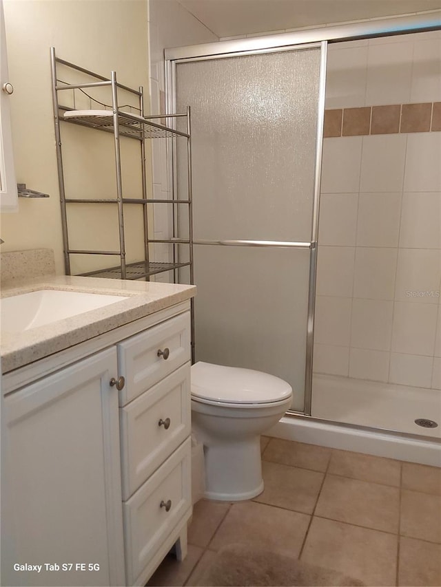 bathroom featuring a stall shower, vanity, tile patterned flooring, and toilet