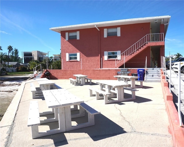 back of property with stairway, stucco siding, and a patio