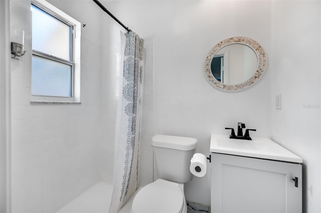 bathroom featuring tiled shower, toilet, and vanity