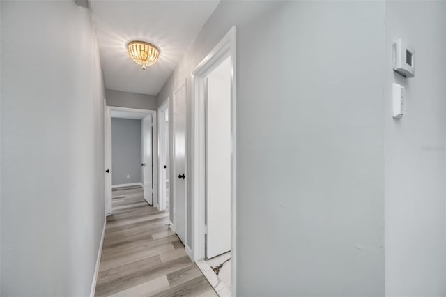 hallway with light wood-type flooring and baseboards