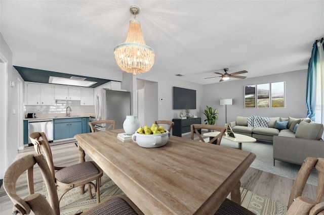 dining space with light wood-style flooring and ceiling fan with notable chandelier