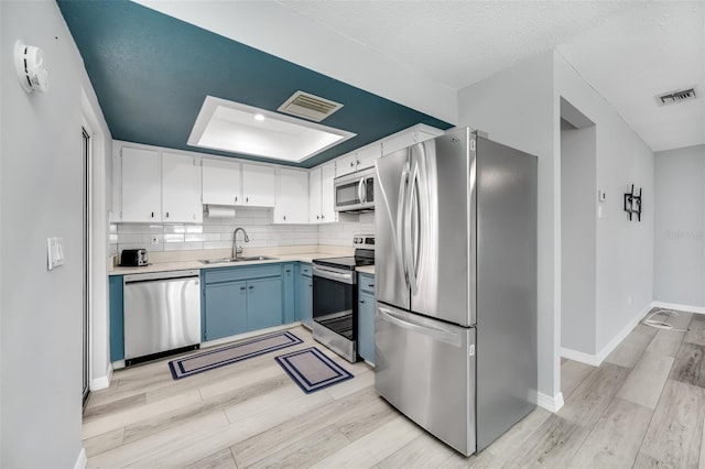 kitchen featuring visible vents, appliances with stainless steel finishes, a raised ceiling, and a sink