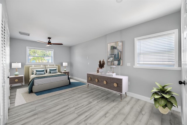 bedroom featuring a ceiling fan, wood finished floors, visible vents, and baseboards