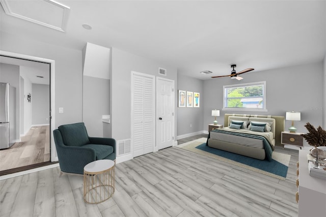 bedroom with visible vents, attic access, light wood-style flooring, and freestanding refrigerator