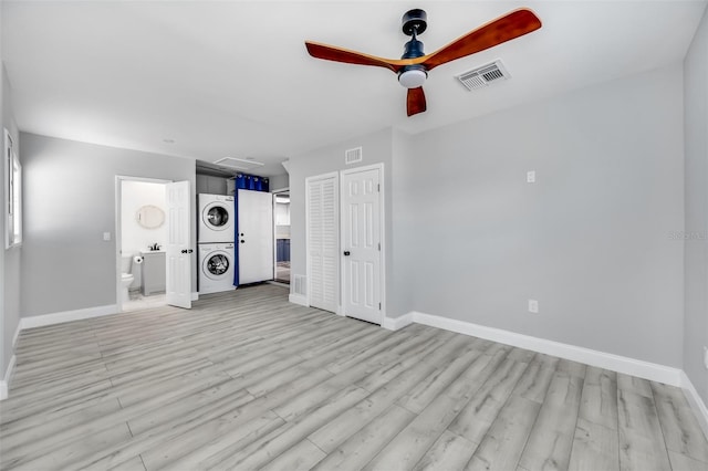 unfurnished bedroom with visible vents, baseboards, attic access, light wood-style flooring, and stacked washer and clothes dryer