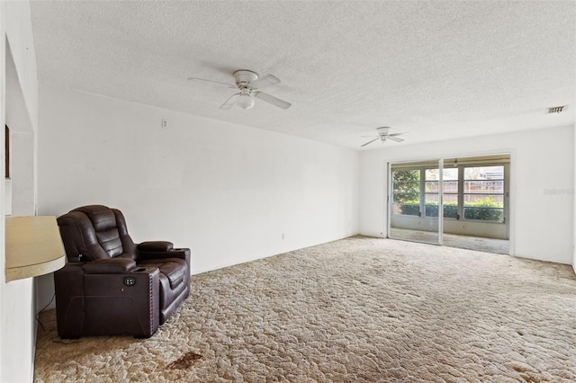 living area with visible vents, a textured ceiling, carpet, and a ceiling fan