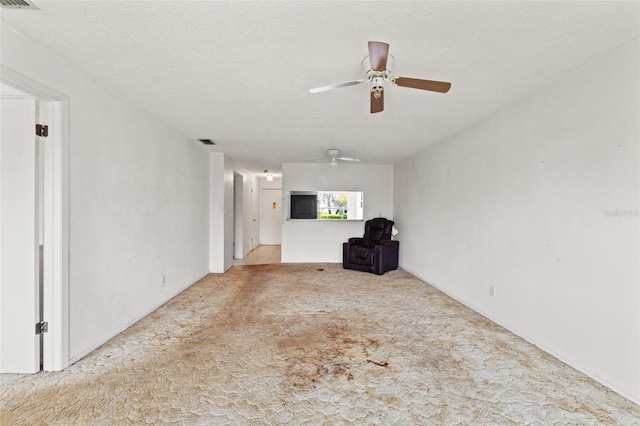 unfurnished living room featuring visible vents, carpet floors, a textured ceiling, and ceiling fan