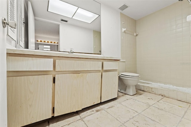 bathroom featuring visible vents, toilet, vanity, and a tile shower