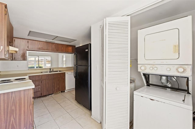 kitchen featuring light tile patterned floors, stacked washing maching and dryer, freestanding refrigerator, light countertops, and dishwasher