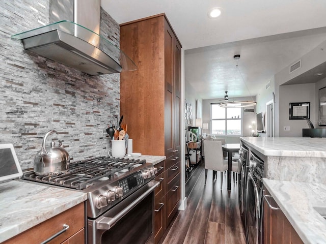 kitchen featuring visible vents, backsplash, gas range, brown cabinets, and wall chimney exhaust hood