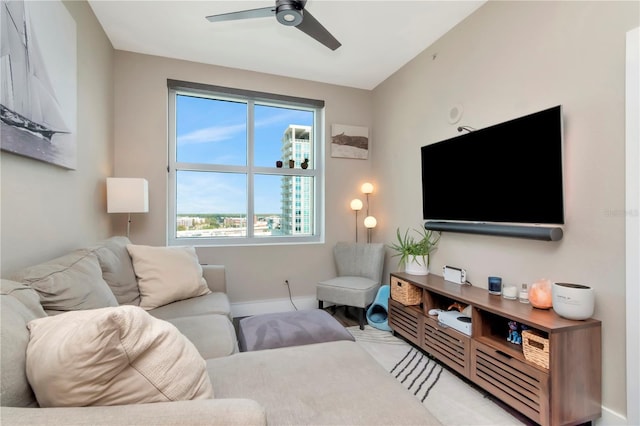 living area with baseboards and ceiling fan