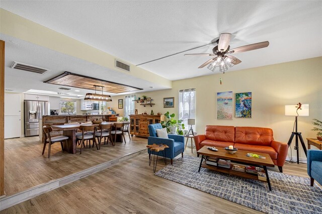 living area with a ceiling fan, visible vents, and light wood-type flooring