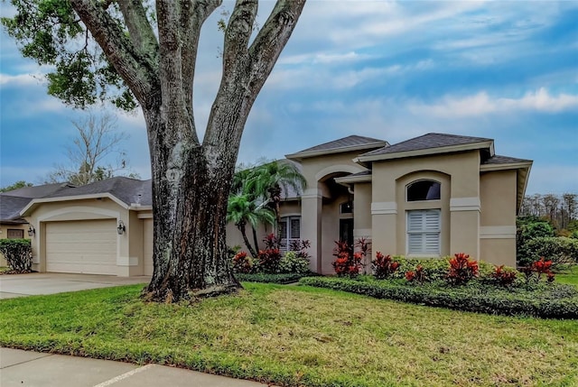 view of front of home with stucco siding, a front yard, concrete driveway, and an attached garage