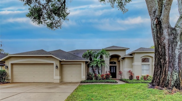 view of front facade featuring concrete driveway, an attached garage, a front yard, and stucco siding