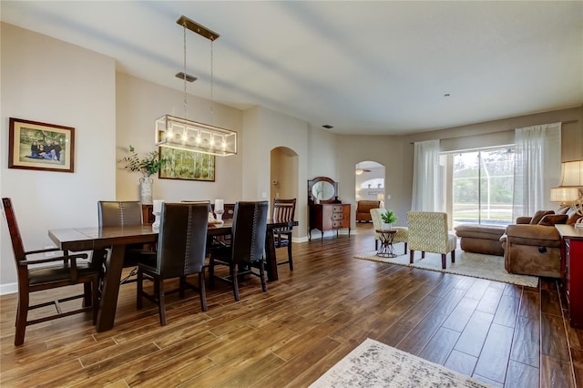 dining space featuring baseboards, arched walkways, and wood finished floors