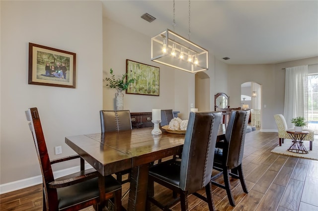 dining room featuring visible vents, arched walkways, baseboards, and wood tiled floor