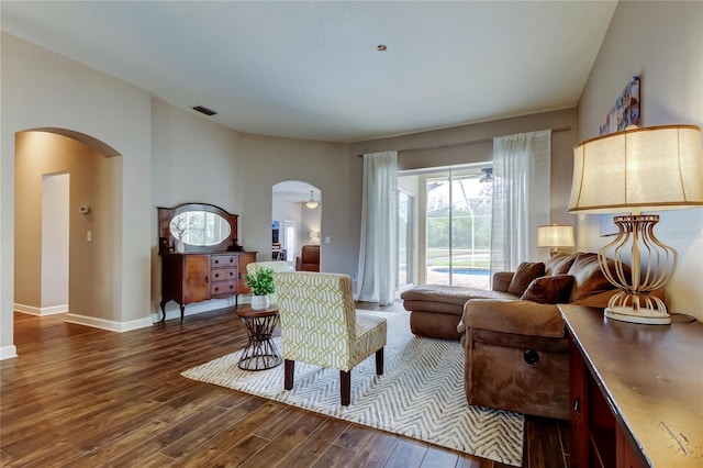 living area with arched walkways, visible vents, baseboards, and wood finished floors