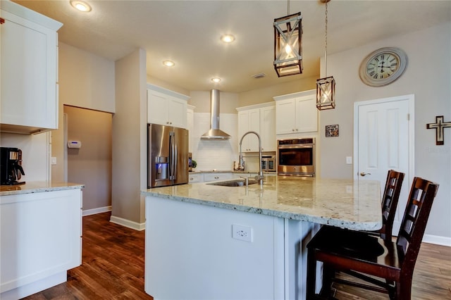 kitchen with stainless steel appliances, dark wood-style floors, white cabinets, and wall chimney range hood