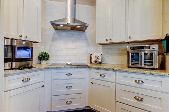 kitchen with black electric cooktop, white cabinets, decorative backsplash, and wall chimney range hood