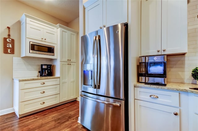 kitchen with decorative backsplash, light stone countertops, stainless steel appliances, and wood finished floors