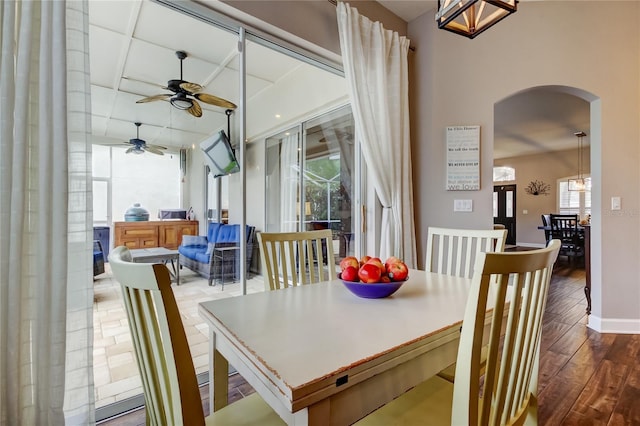 dining area with wood finished floors, arched walkways, and ceiling fan