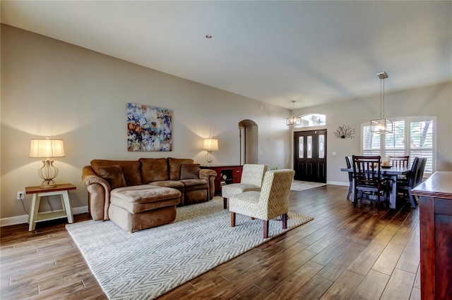 living room featuring wood finished floors, arched walkways, and baseboards