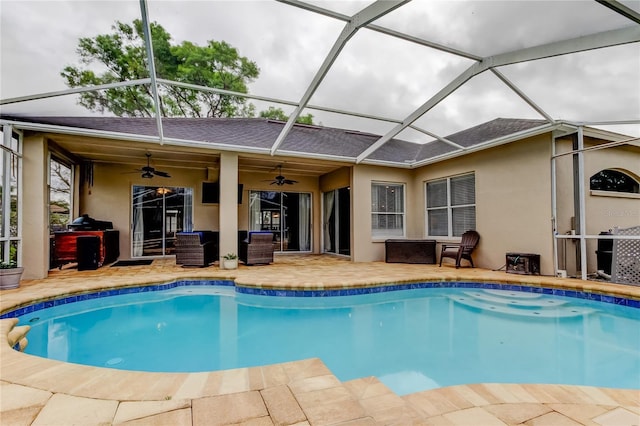 outdoor pool with a patio area, glass enclosure, and ceiling fan