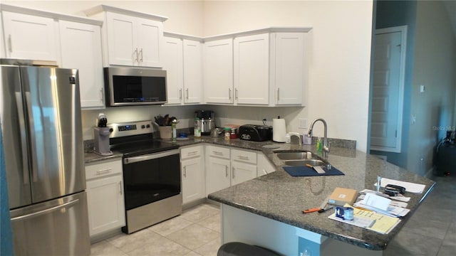 kitchen featuring a sink, a peninsula, white cabinets, and stainless steel appliances